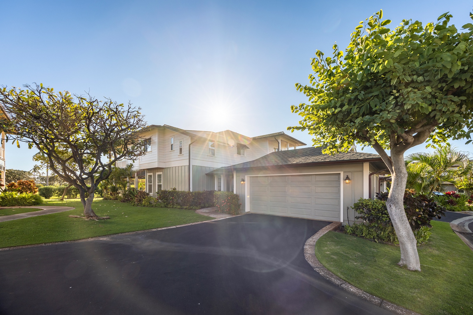 A modern vacation home nestled among tropical landscaping with mature trees and manicured lawns in a peaceful residential setting.