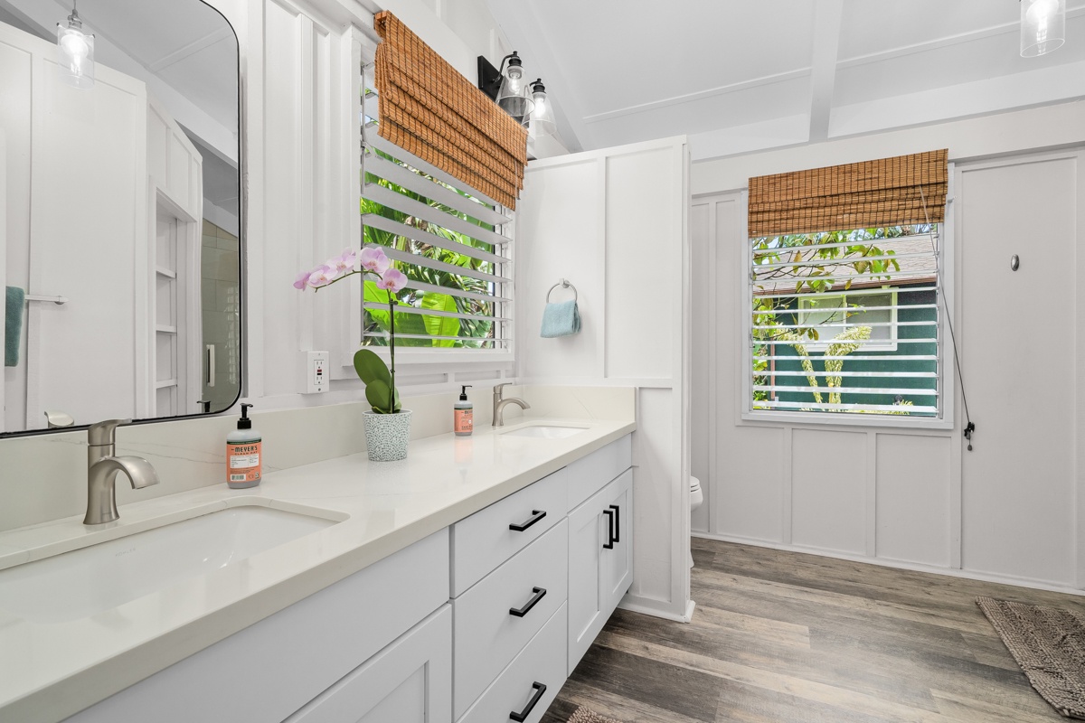 Hanalei Vacation Rentals, Hale Kanani (Kaua'i) TVNC 1342 - Crisp white vanity, wide mirror, and a window cracked to the green outside.