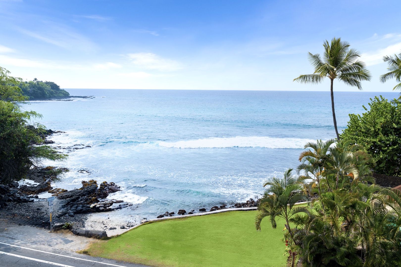 Kailua Kona Vacation Rentals, Royal Kahili 401A - Idyllic oceanfront scenery featuring palm trees, serene blue waters, and rocky shores.