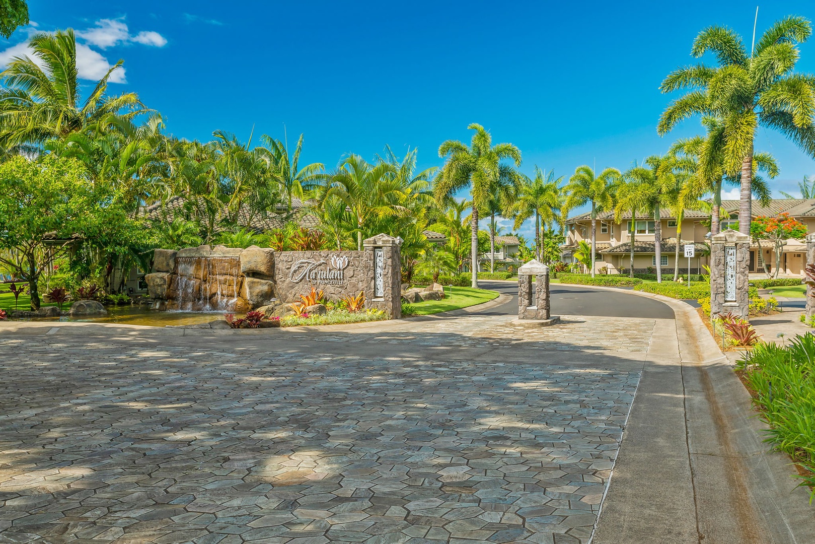 Princeville Vacation Rentals, Kaiulani #8 - Drive in over stone pavers between rock walls and rows of palms.