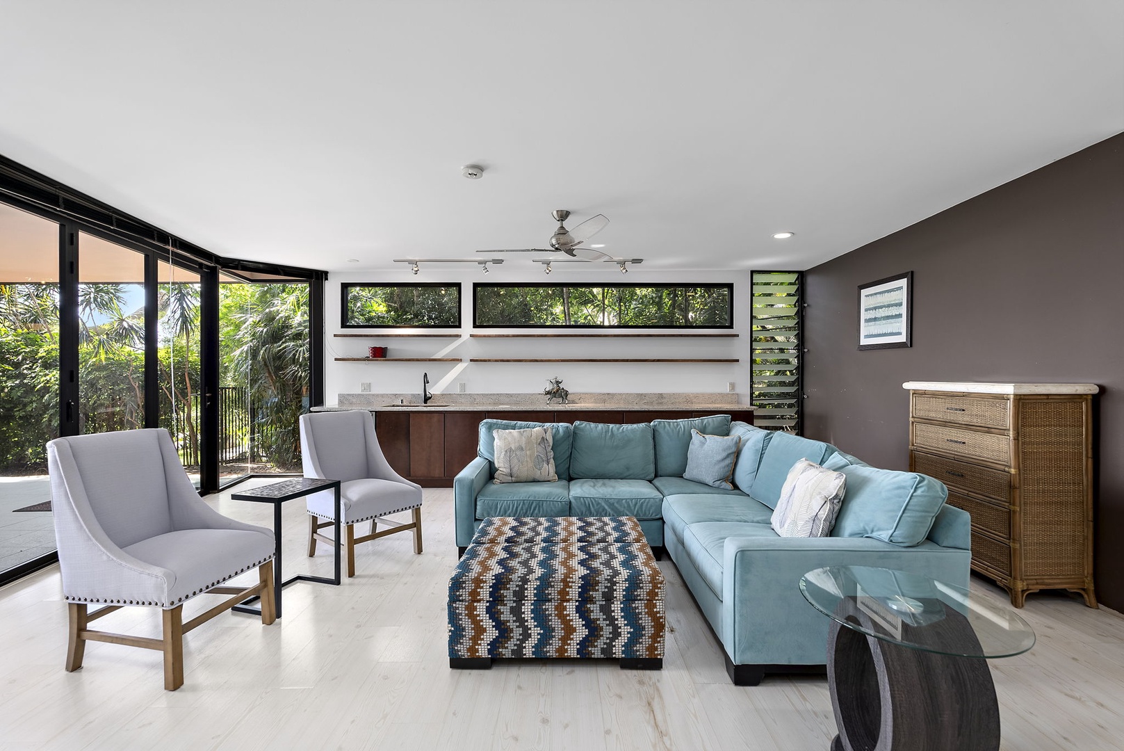 Honolulu Vacation Rentals, Tantalus Glass House (3 BD) - Stylish open-plan living space with plush sectional seating and tropical garden views through floor-to-ceiling windows.