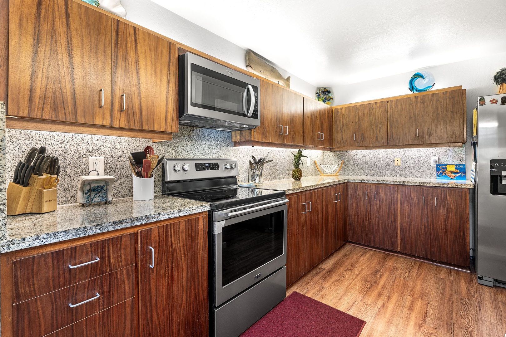 Kailua Kona Vacation Rentals, Kanaloa at Kona 701 - Your modern kitchen features warm wood cabinets, granite countertops, and stainless steel appliances—everything you need to create memorable meals.