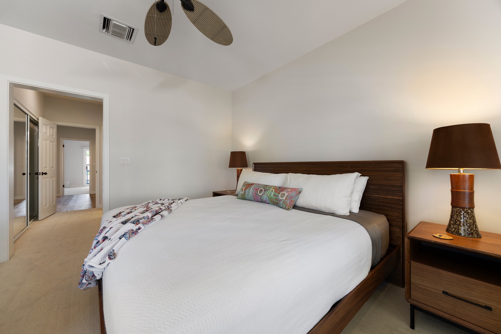 Sink into crisp white linens and modern comfort in your serene bedroom retreat, complete with stylish furnishings and gentle ceiling fan breezes.