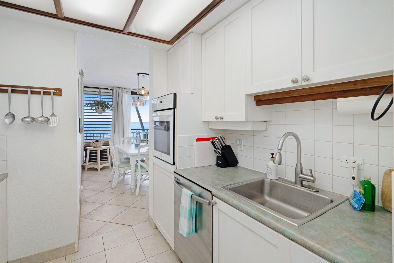Kihei Vacation Rentals, Punahoa Beach 205 - Suds up at the kitchen sink while the ocean holds steady past the dining table.