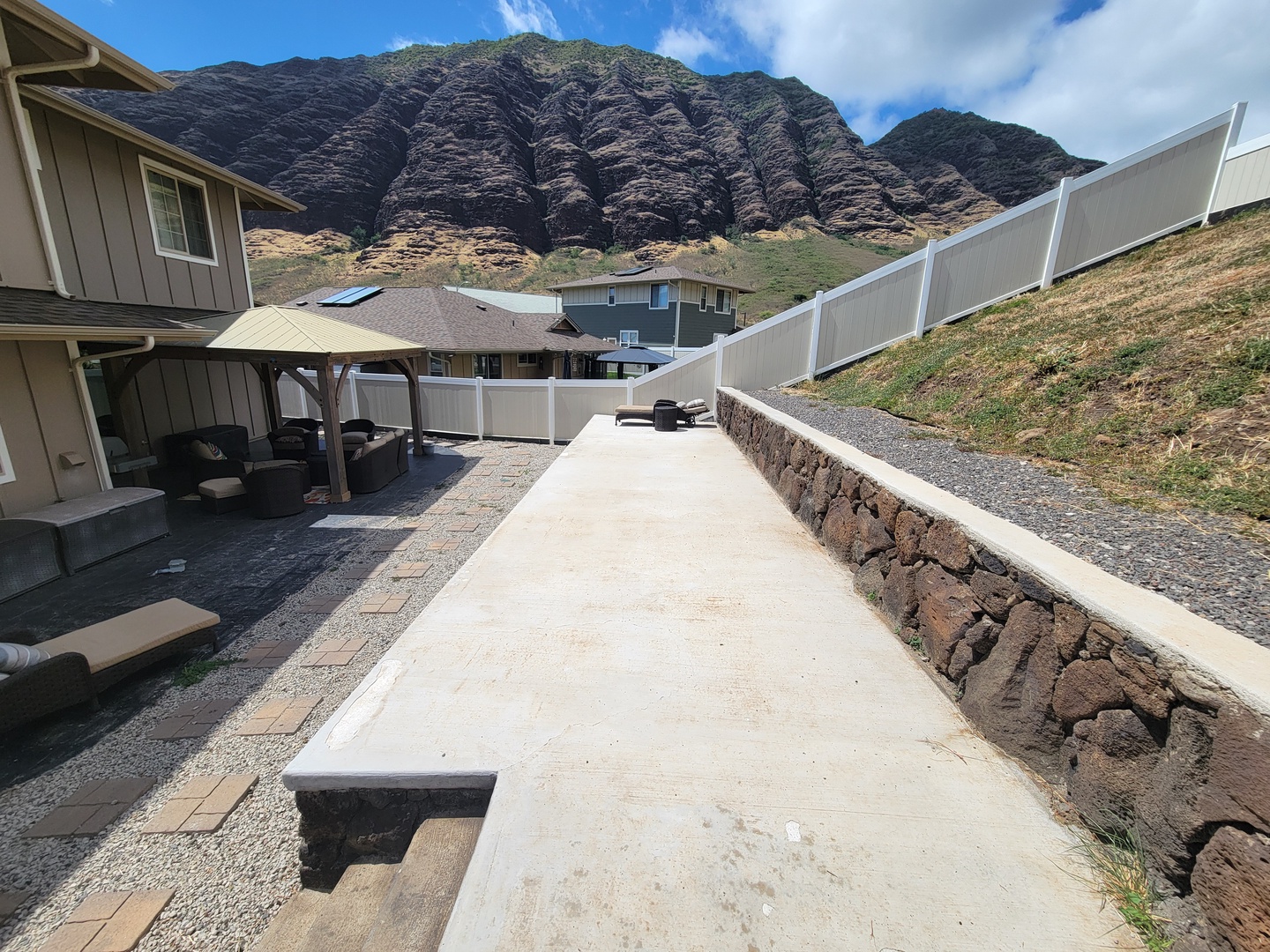 Makaha Valley Vacation Rentals, Makaha Valley Hale Kai** - Expansive side yard with mountain views, leading to shaded outdoor seating and BBQ area.
