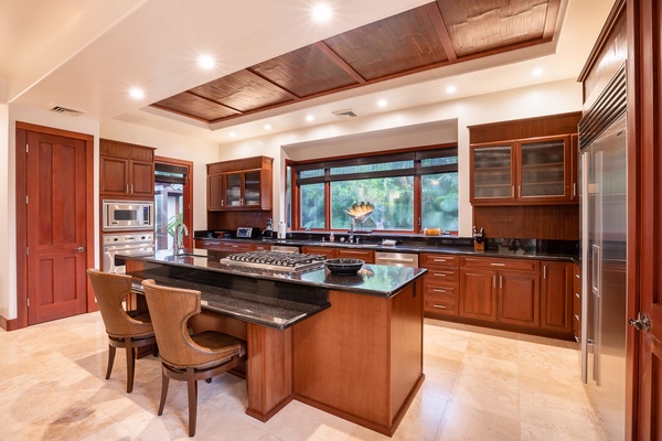 Kamuela Vacation Rentals, Canoe House & Beach Walker at Champion Ridge - Spacious kitchen with rich wood cabinetry, a large central island, and ample counter space, perfect for preparing meals and entertaining guests.