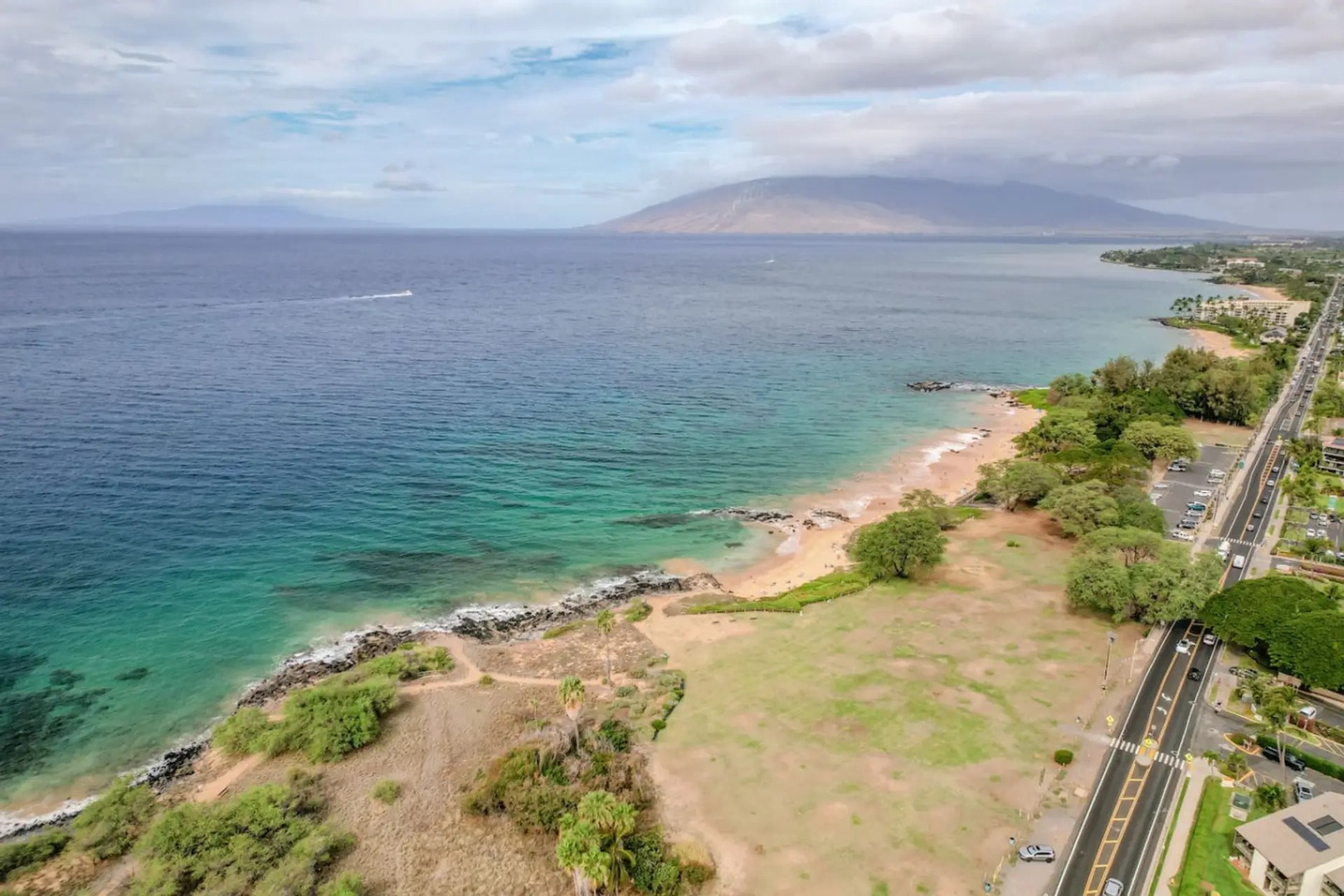 Kihei Vacation Rentals, Maui Kamaole E103 - Coastline curves along the road just past the property, ocean on one side and green fields on the other.