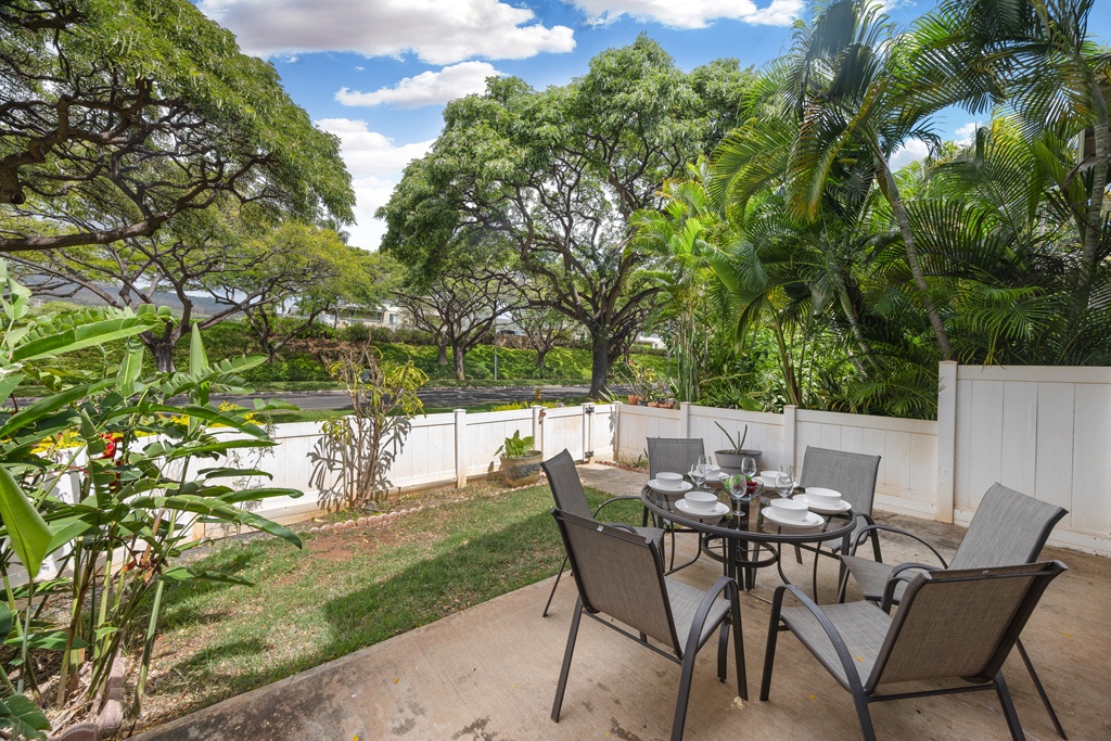 Dine al fresco at your private patio table surrounded by tropical greenery and mature trees creating a peaceful garden atmosphere.