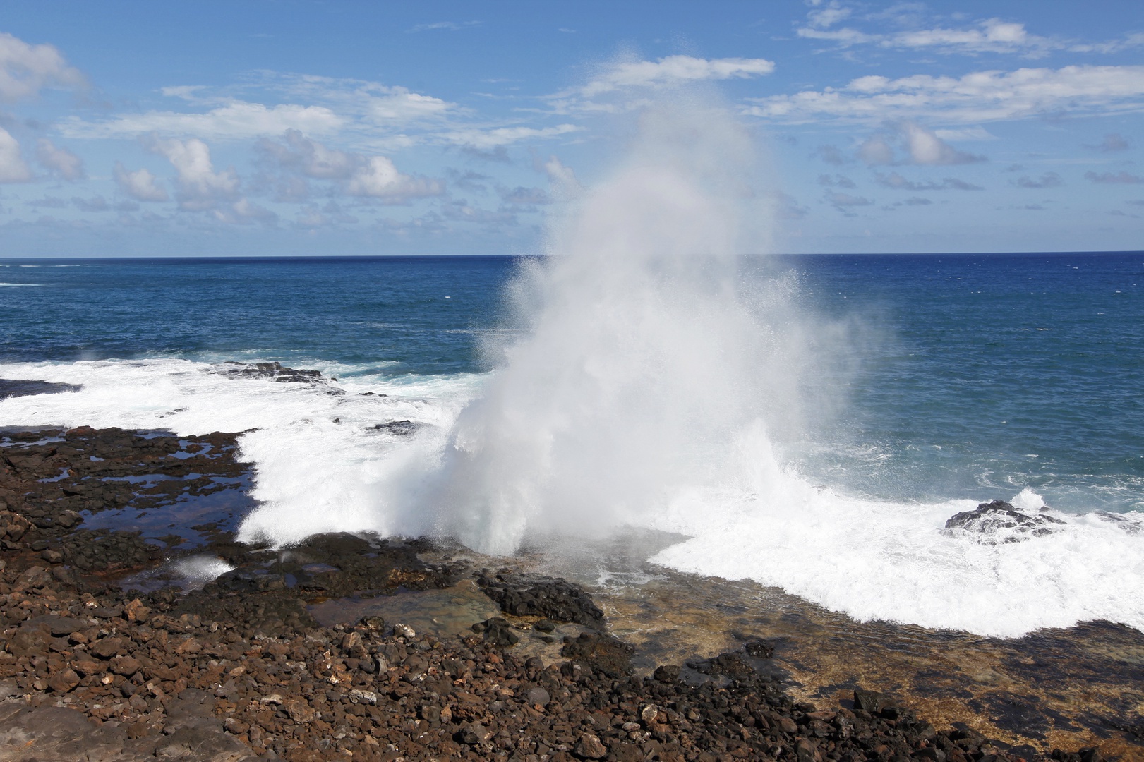 Koloa Vacation Rentals, Pili Mai 6J - Dramatic ocean waves crash against rocky coastline, creating spectacular water geysers under bright blue skies.