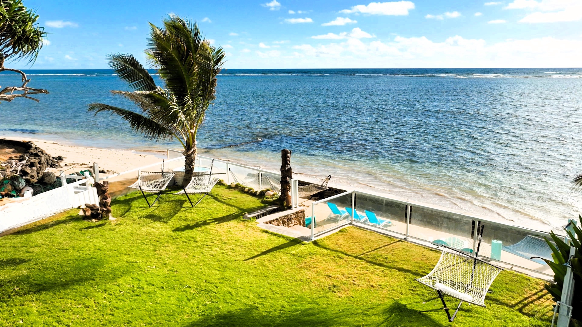 Hauula Vacation Rentals, Private Beach Paradise - The grass runs down to sand and turquoise water, one palm marking the edge.