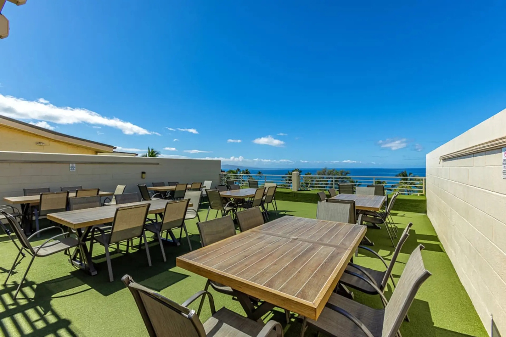Kihei Vacation Rentals, Kamaole Beach Royal 610 - The whole group fits at the rooftop's wood dining tables, ocean stretching out behind them.