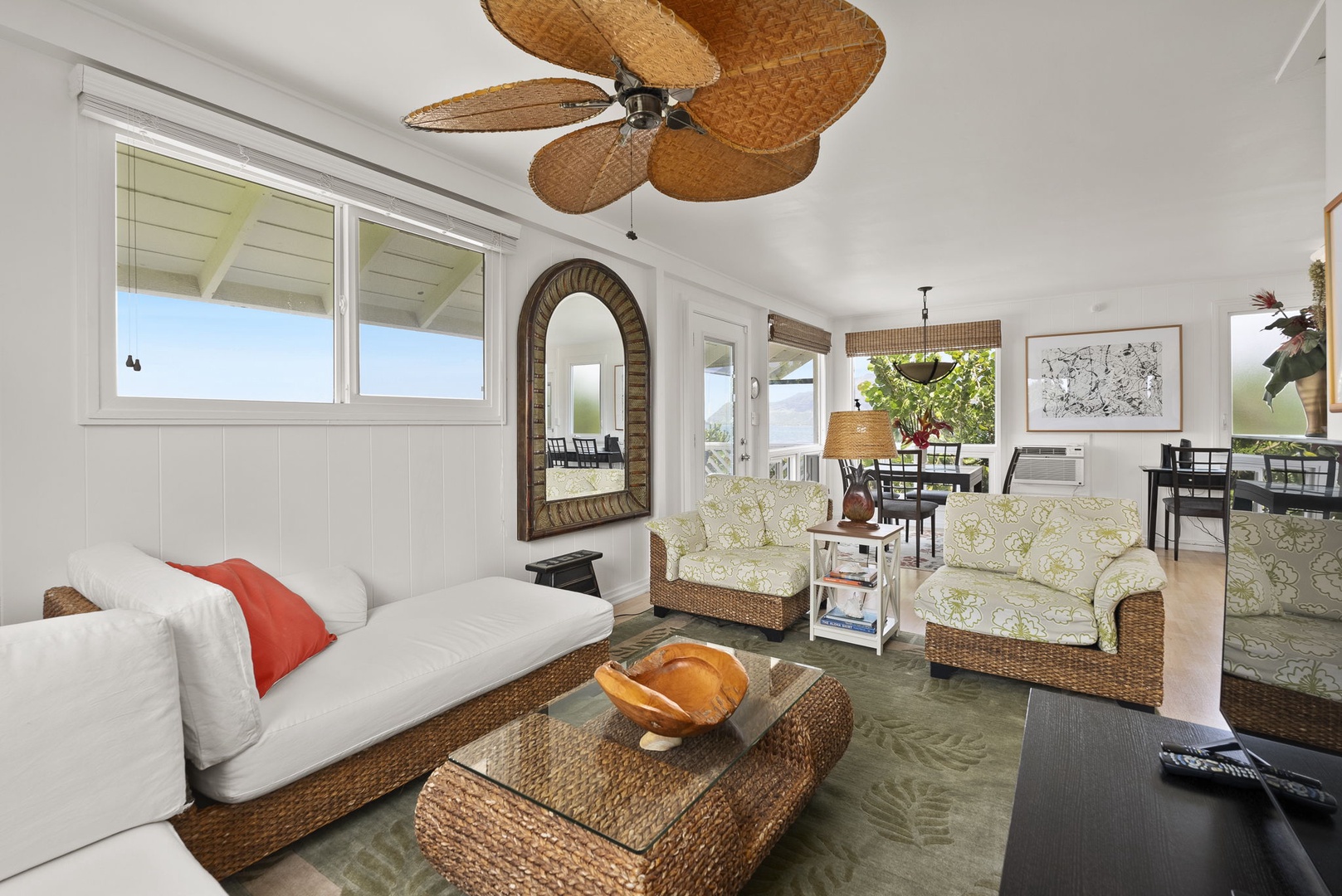 Waianae Vacation Rentals, Ma'ili Blue Estate - Your tropical-inspired cottage living room has wicker furniture, ceiling fan, and bright windows creating a breezy island atmosphere.