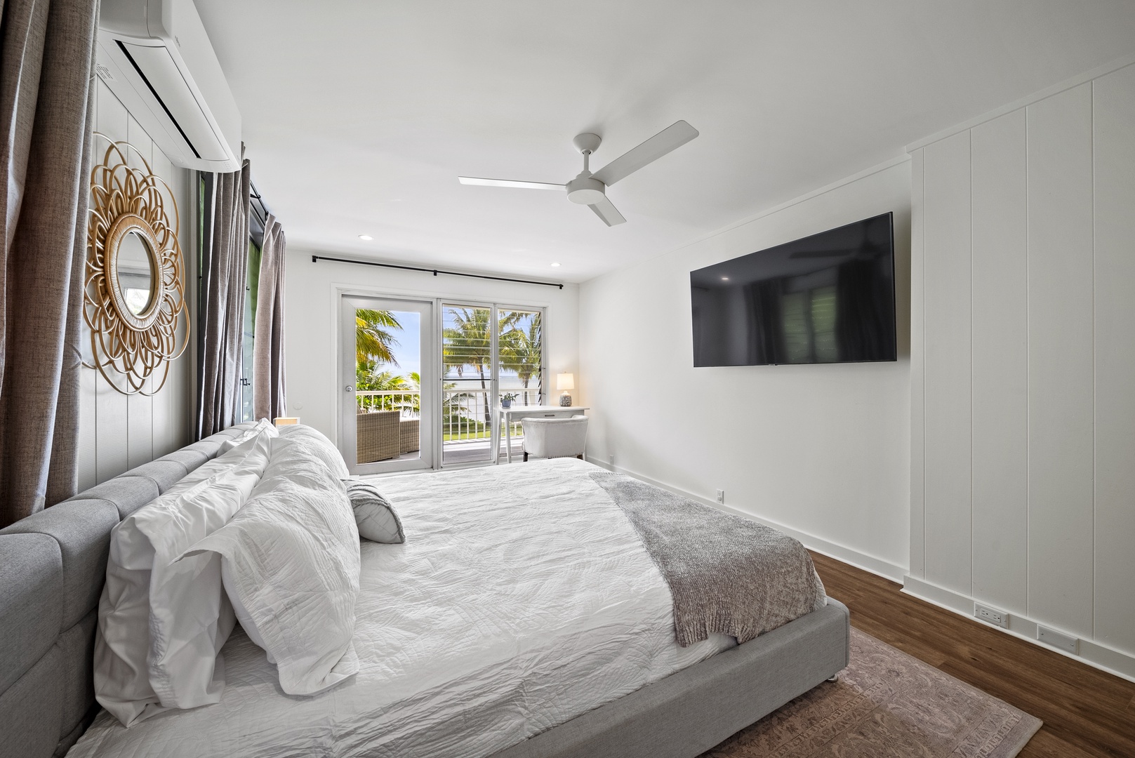 Honolulu Vacation Rentals, Honolulu Beachfront Retreat - Coastal-style guest bedroom with a king-sized bed, flat-screen TV, and direct access to the balcony for fresh ocean breezes.
