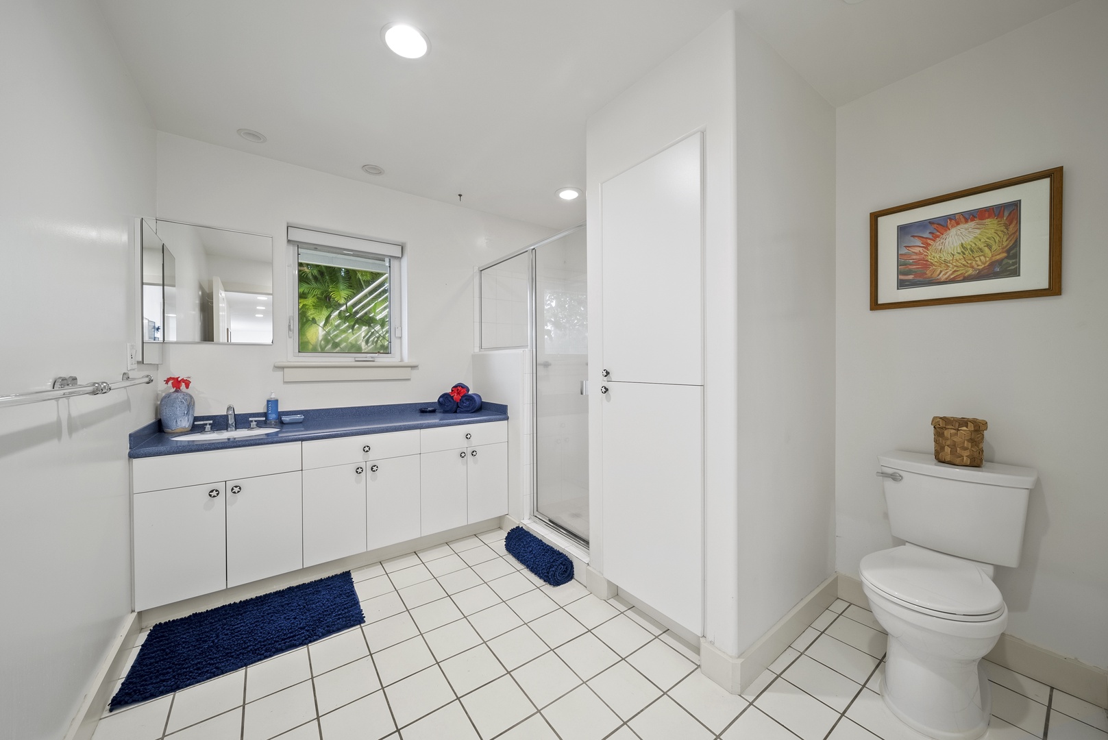 Haleiwa Vacation Rentals, Ka Hale Hau'oli - Your spacious guest bathroom features crisp white cabinetry, a deep blue countertop, and plenty of storage for your toiletries.