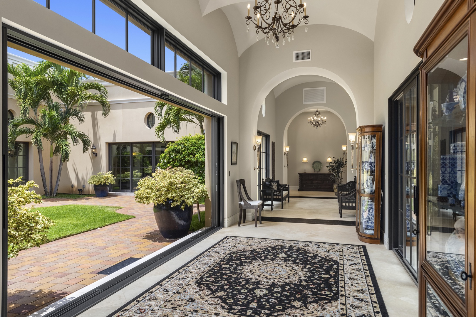 Honolulu Vacation Rentals, The Kahala Mansion Event Venue - Bright hallway with high ceilings and arched windows, connecting indoor and outdoor living spaces seamlessly.