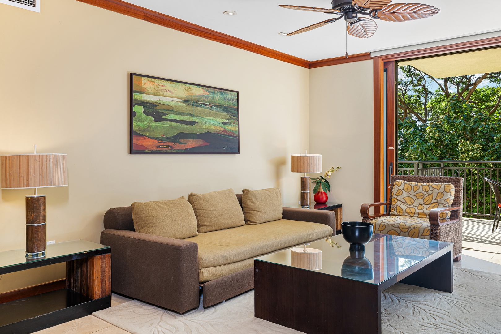 Settle into your peaceful living room with tropical breezes and lush garden views just beyond your private balcony. Relax on plush seating under the ceiling fan's gentle air.