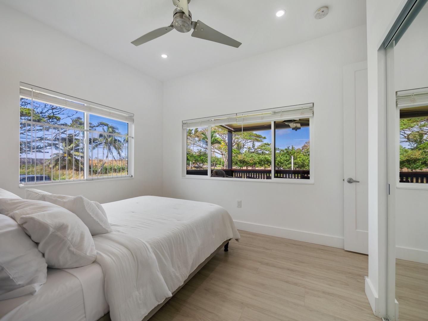 Haleiwa Vacation Rentals, Sunset Beach Island Retreat - This bright and airy primary bedroom features large windows that let in natural light and offer serene views of the surrounding greenery.