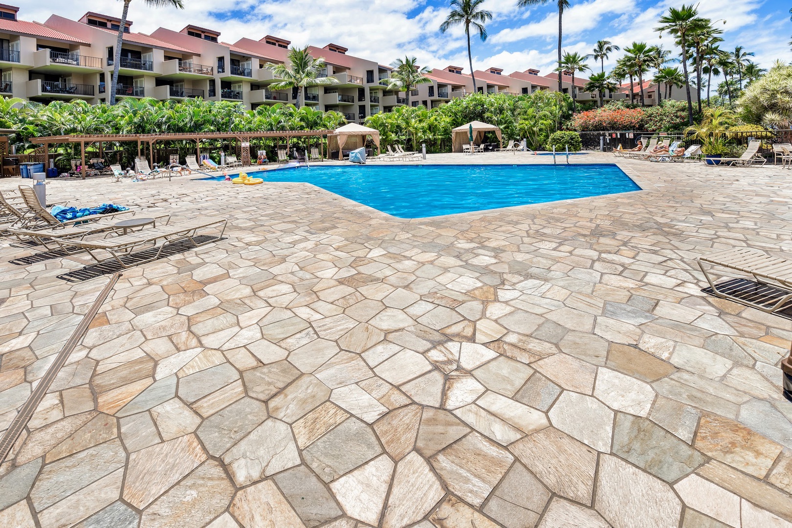 Kihei Vacation Rentals, Kamaole Sands 5310 - Claim a lounge chair by the community pool, palms and the pergola shading the deck.