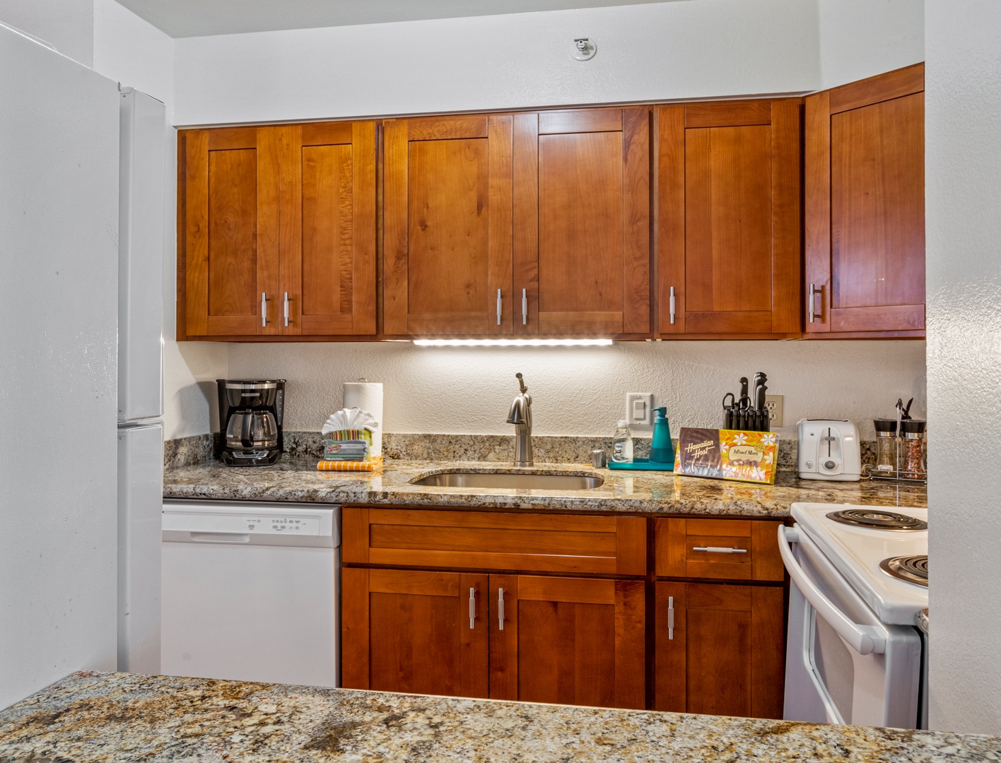 Lahaina Vacation Rentals, Royal Kahana 308 - The kitchen features wooden cabinetry, granite countertops, and modern appliances for convenient meal preparation.