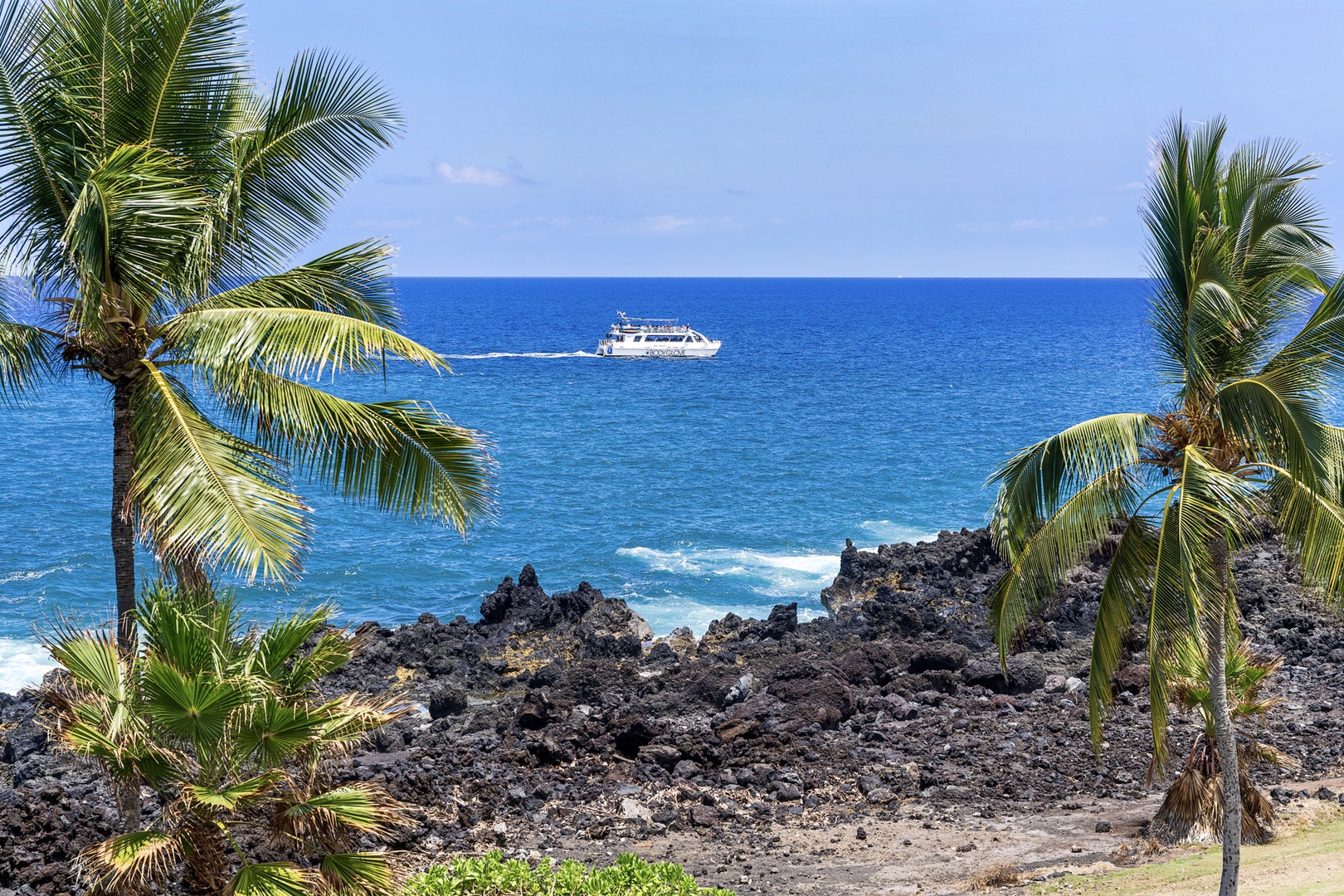 Kailua Kona Vacation Rentals, Kanaloa at Kona 1606 - Palms frame the lava-rock shoreline where boats drift across the blue.