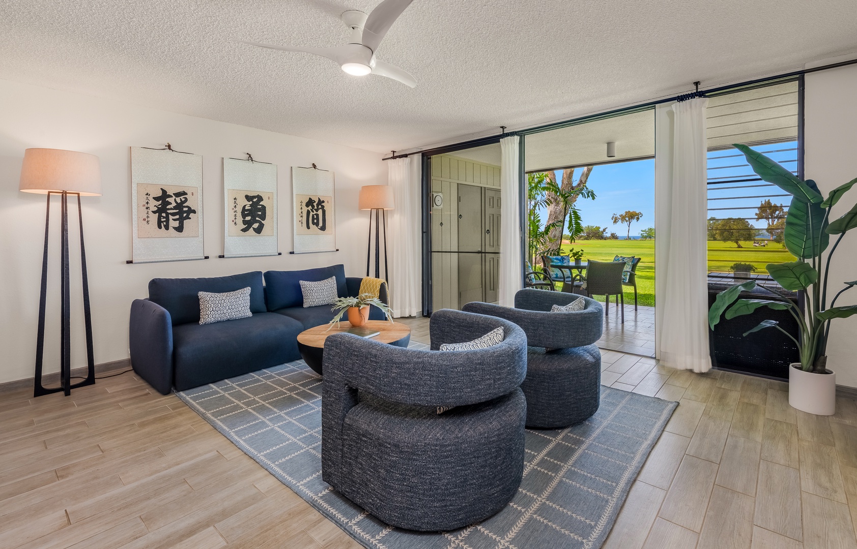 Waikoloa Vacation Rentals, Waikoloa Villas A107 - Settle into your stylish living room where sleek navy sofas and modern ottomans await, while tropical views unfold beyond sliding doors.