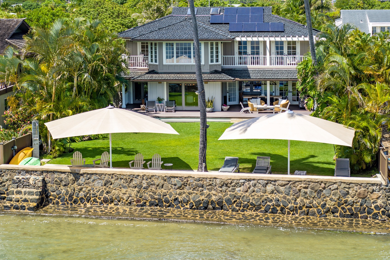 Honolulu Vacation Rentals, Moana Lani - Main House - Oceanfront from the air: lawn, shade umbrellas, and a seawall at the water’s edge.