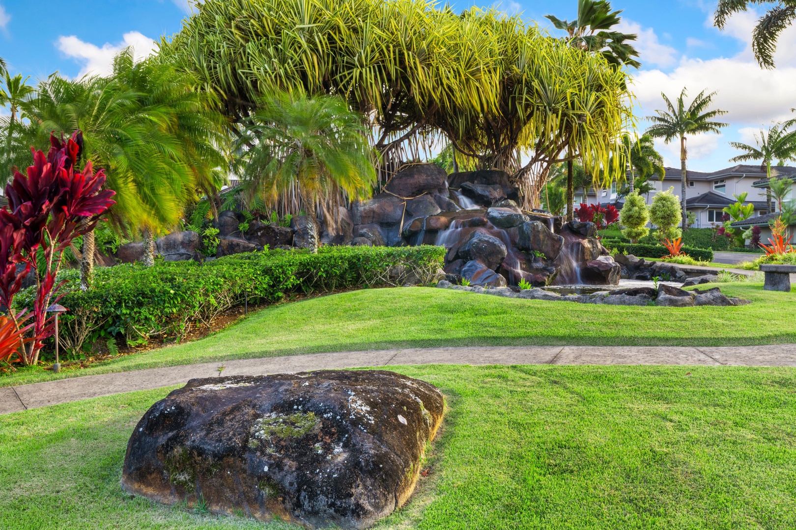 Princeville Vacation Rentals, Noelani Kai - Trailing greenery drapes over stacked lava rock along the lawn's edge.