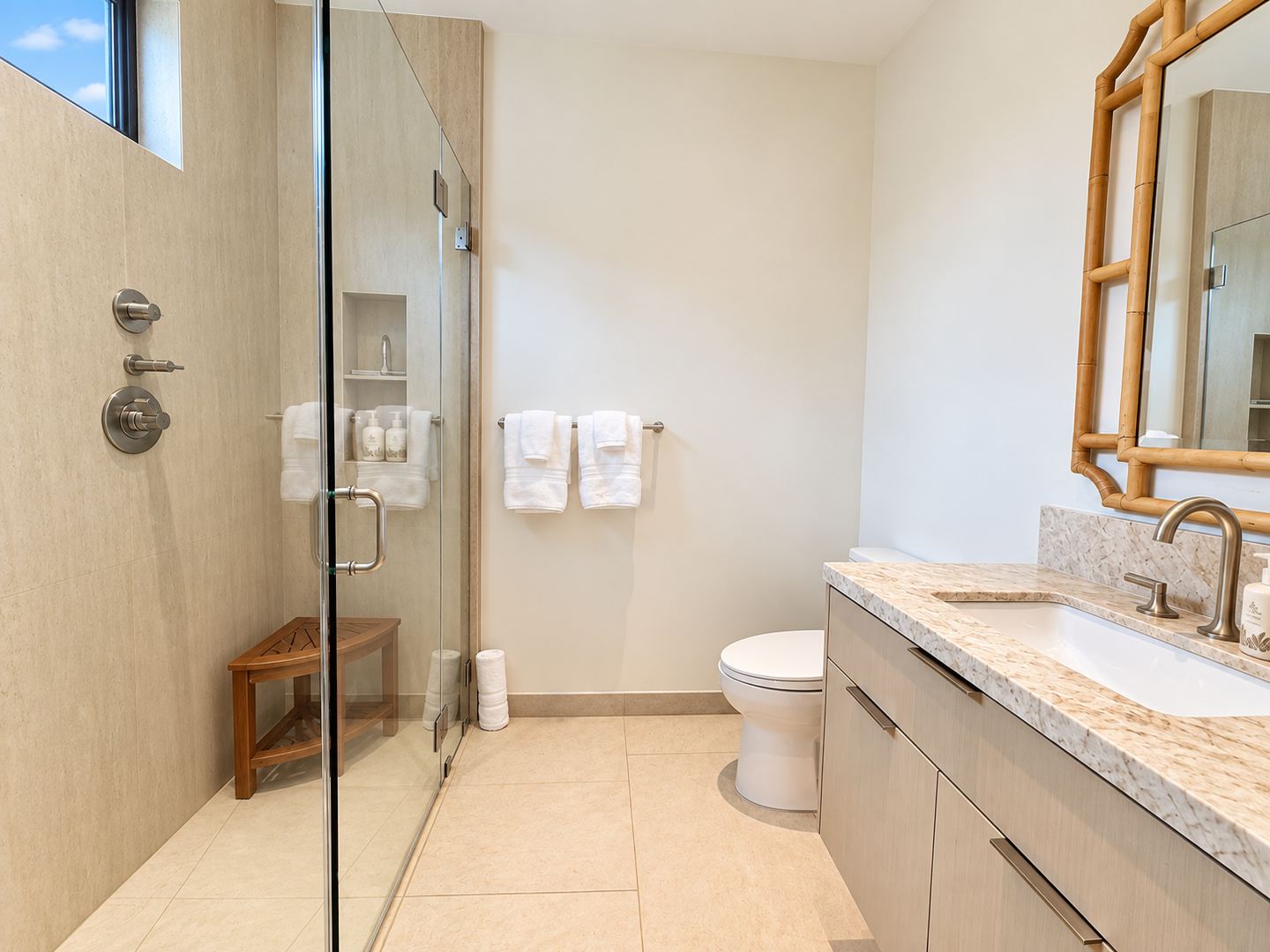 Kamuela Vacation Rentals, 6BD Mauna Lani Lux Golf Estate (5) at One Ocean - A bright ensuite bathroom pairs warm stone finishes with a bamboo-framed mirror and a glass walk-in shower