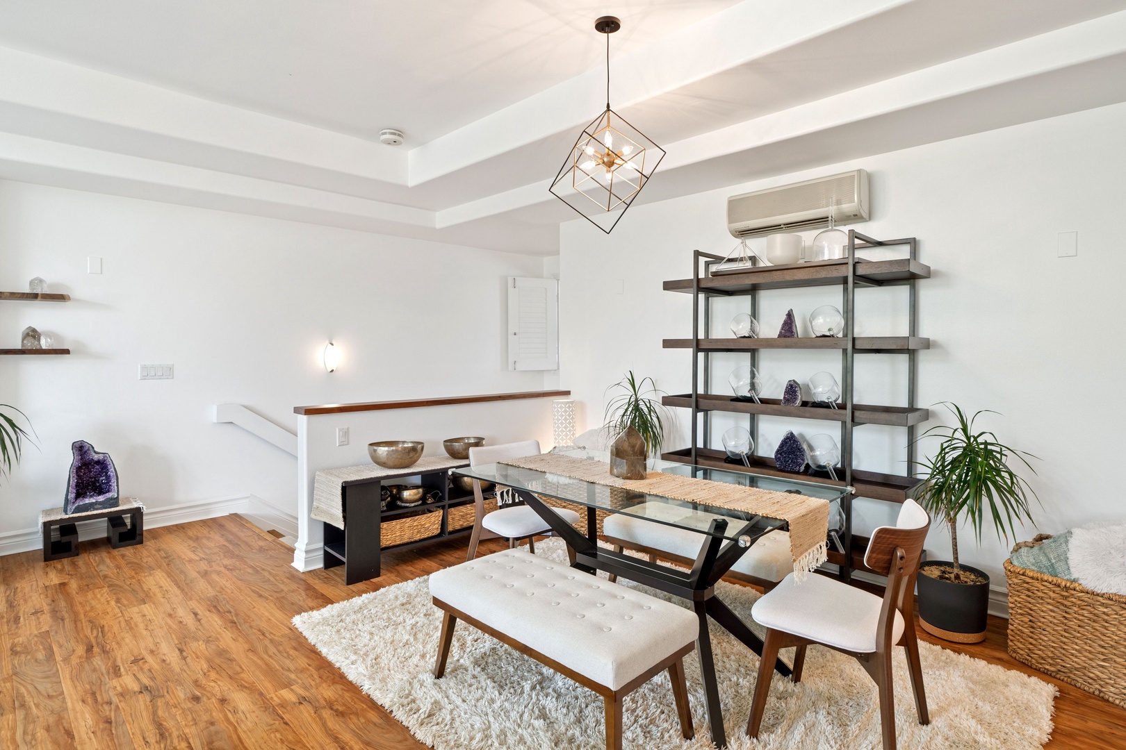 Princeville Vacation Rentals, Tropical Elegance - Metal-framed shelves adorned with decor items and plants enhance the room's ambiance, all set upon a soft, textured rug.