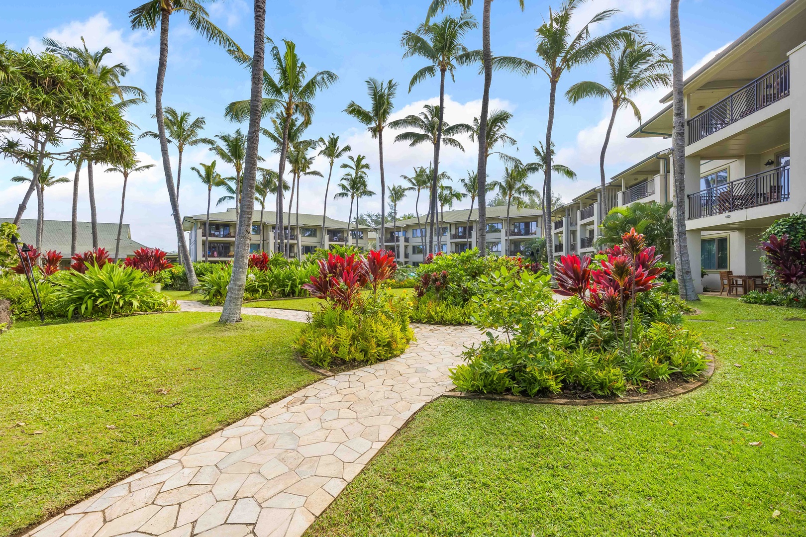 Kahuku Vacation Rentals, Turtle Bay Villas 209 - Tropical resort buildings surrounded by lush gardens and swaying palm trees create a serene Hawaiian atmosphere.