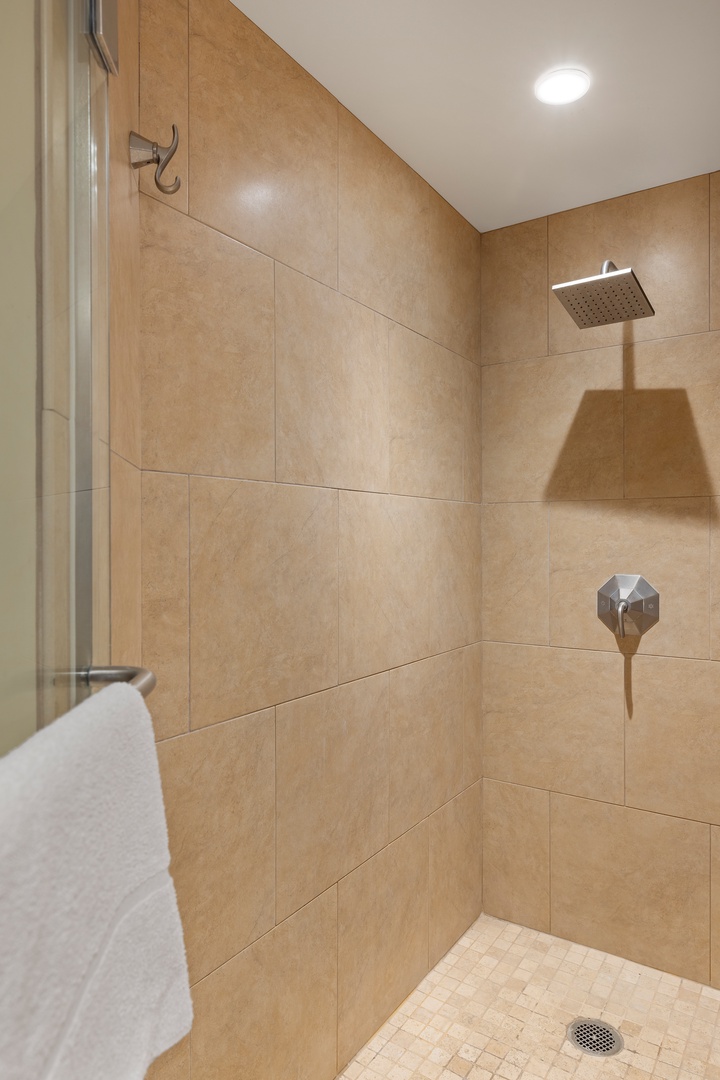 Step into your spacious walk-in shower with rainfall showerhead and modern fixtures, where warm tones create a spa-like retreat for your morning rituals.