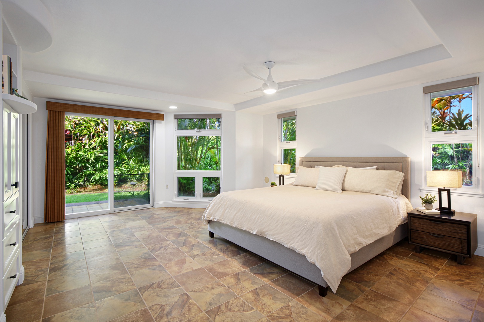 Princeville Vacation Rentals, Villas on the Prince #28 - The spacious primary bedroom is furnished with a comfy king bed, ceiling fan, direct access to the back lanai (porch) with stunning garden views