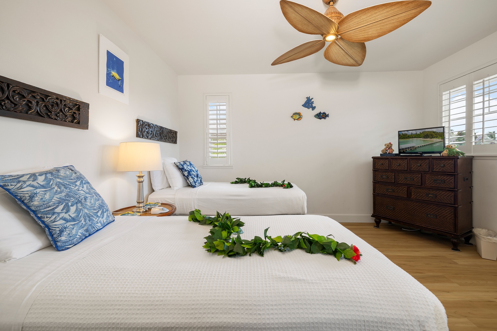 Kapolei Vacation Rentals, Ko Olina Kai 1105E - Your peaceful retreat features two plush beds adorned with fresh tropical greenery, airy island decor, and a breezy ceiling fan to keep you cool and comfortable.