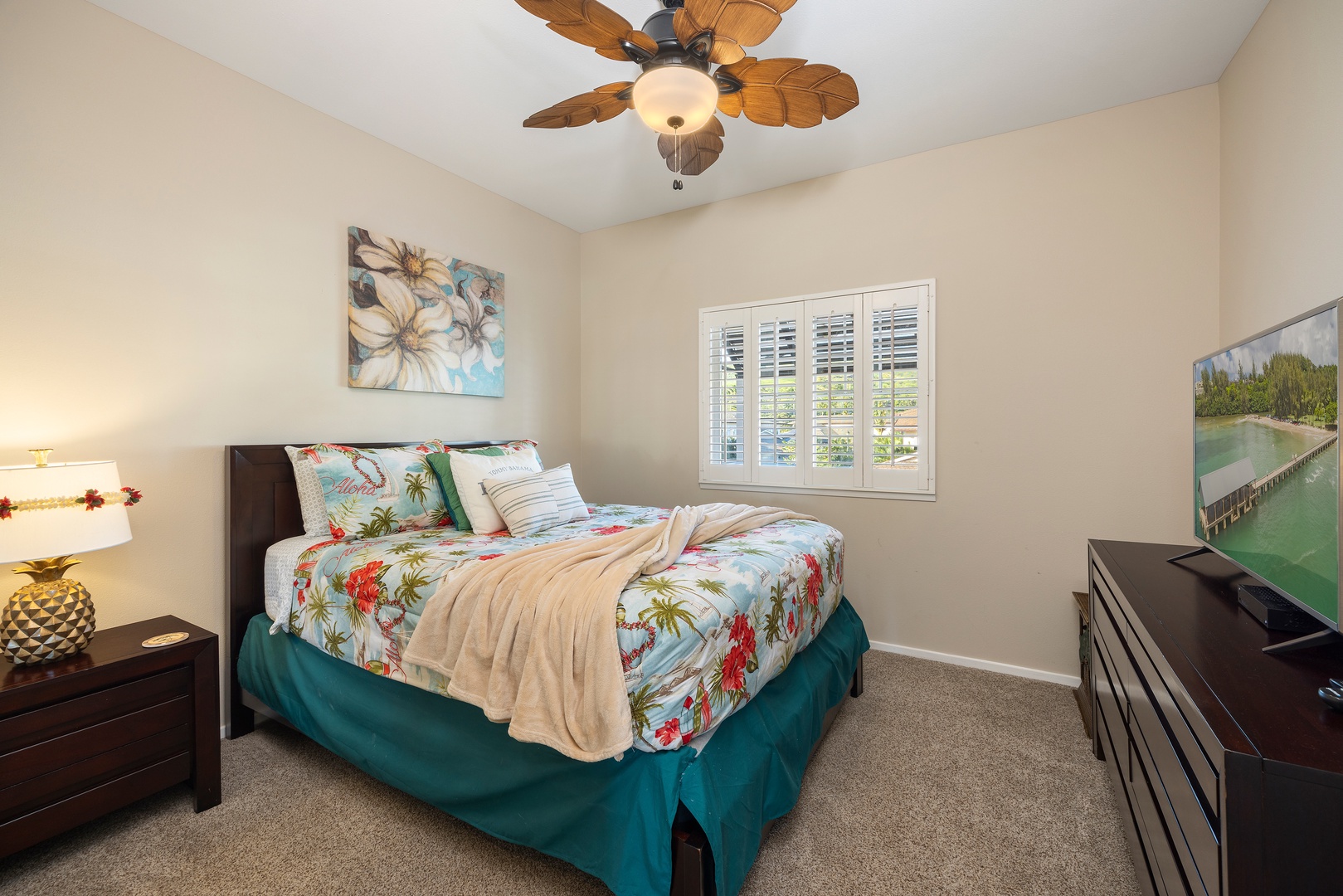 Drift off to tropical dreams in this serene bedroom featuring vibrant island-inspired bedding and gentle ceiling fan breezes.