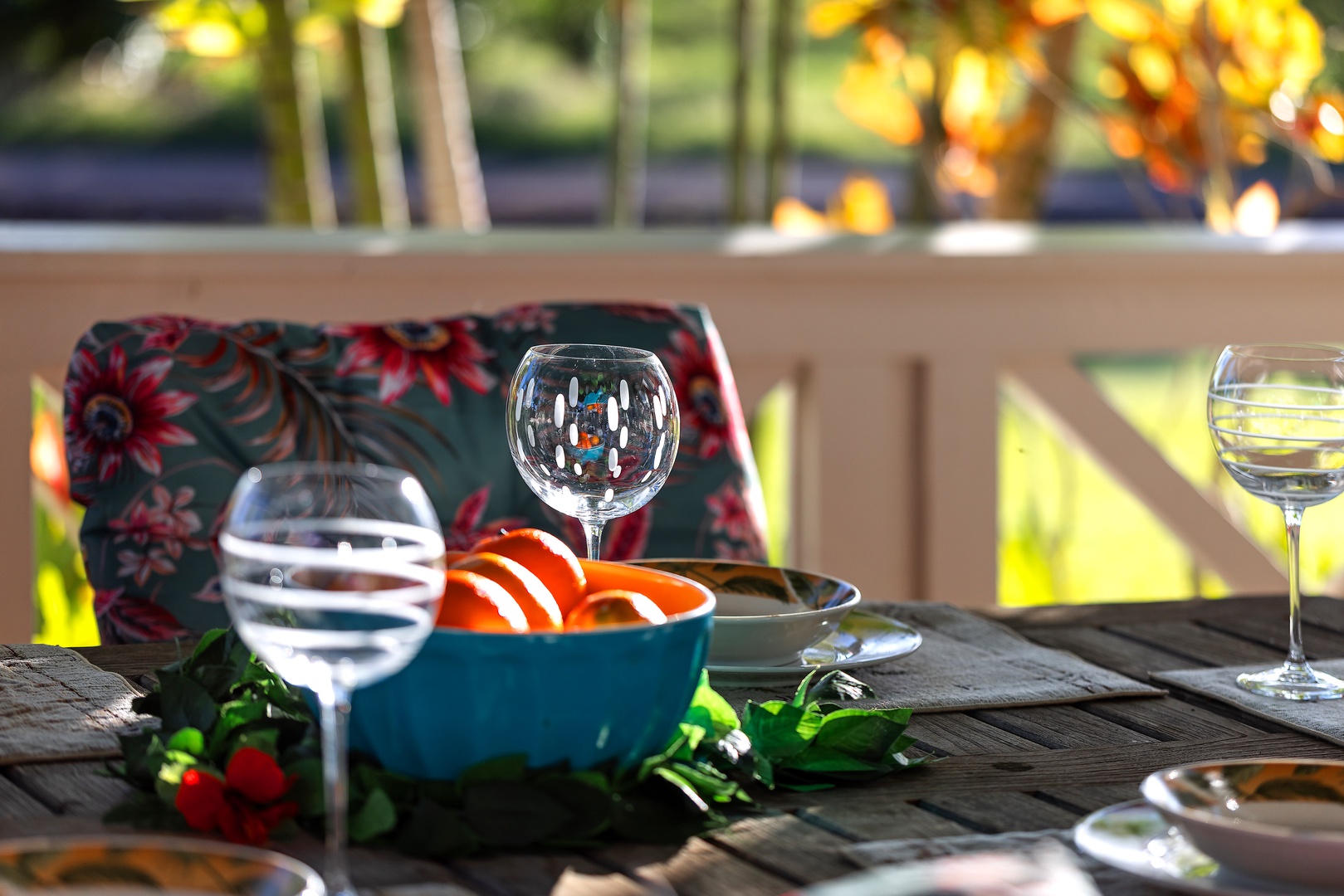 Your outdoor dining table awaits with fresh fruit, wine glasses, and tropical cushions creating the perfect al fresco setting.