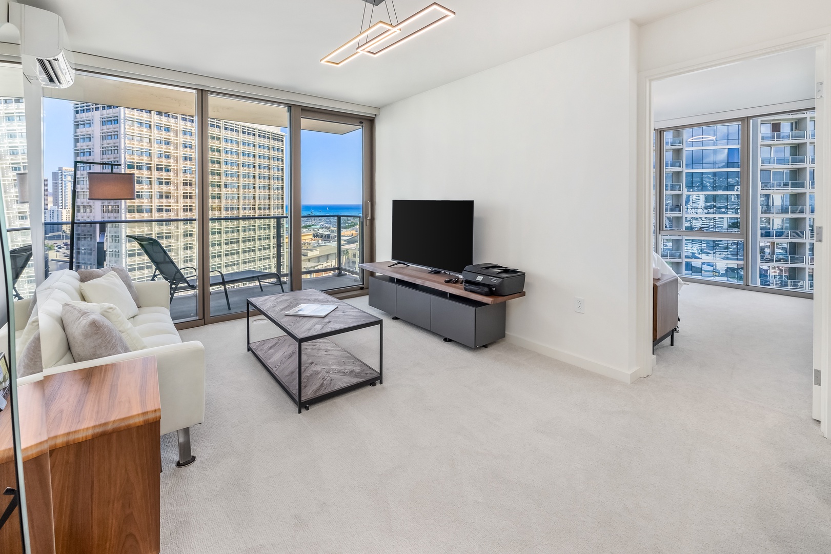 Honolulu Vacation Rentals, Sky Ala Moana #1701 - Spacious living area with a flat-screen TV and floor-to-ceiling windows, offering natural light and access to a private lanai with views.