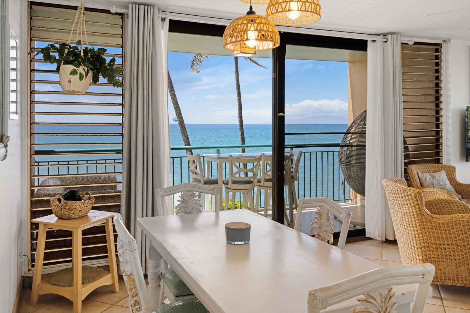 Kihei Vacation Rentals, Punahoa Beach 205 - Woven pendant lights hang low over the table, with the egg chair on the lanai just beyond.