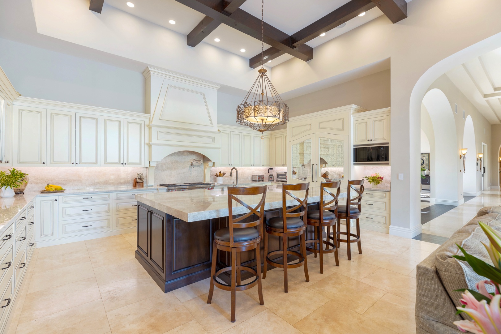 Honolulu Vacation Rentals, The Kahala Mansion Event Venue - Spacious kitchen with a large center island, bar seating, and elegant light fixtures for entertaining and meal prep.