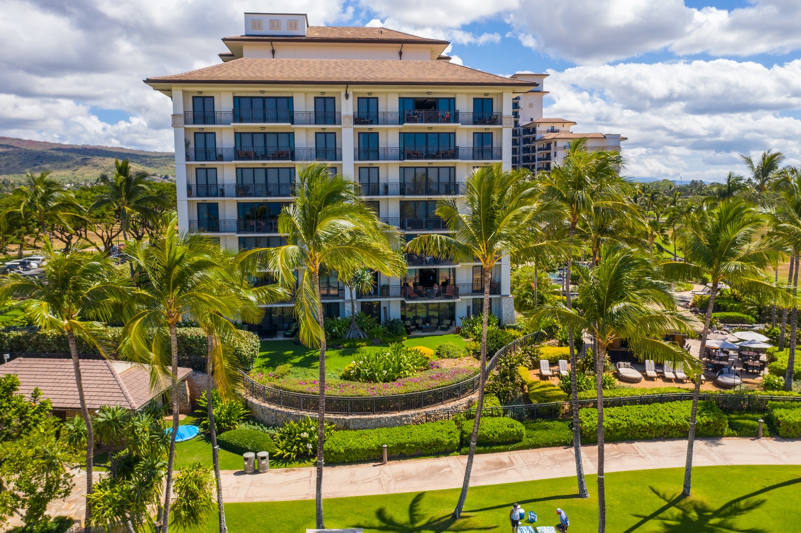 The villa tower rises over the gardens, palms softening the base.