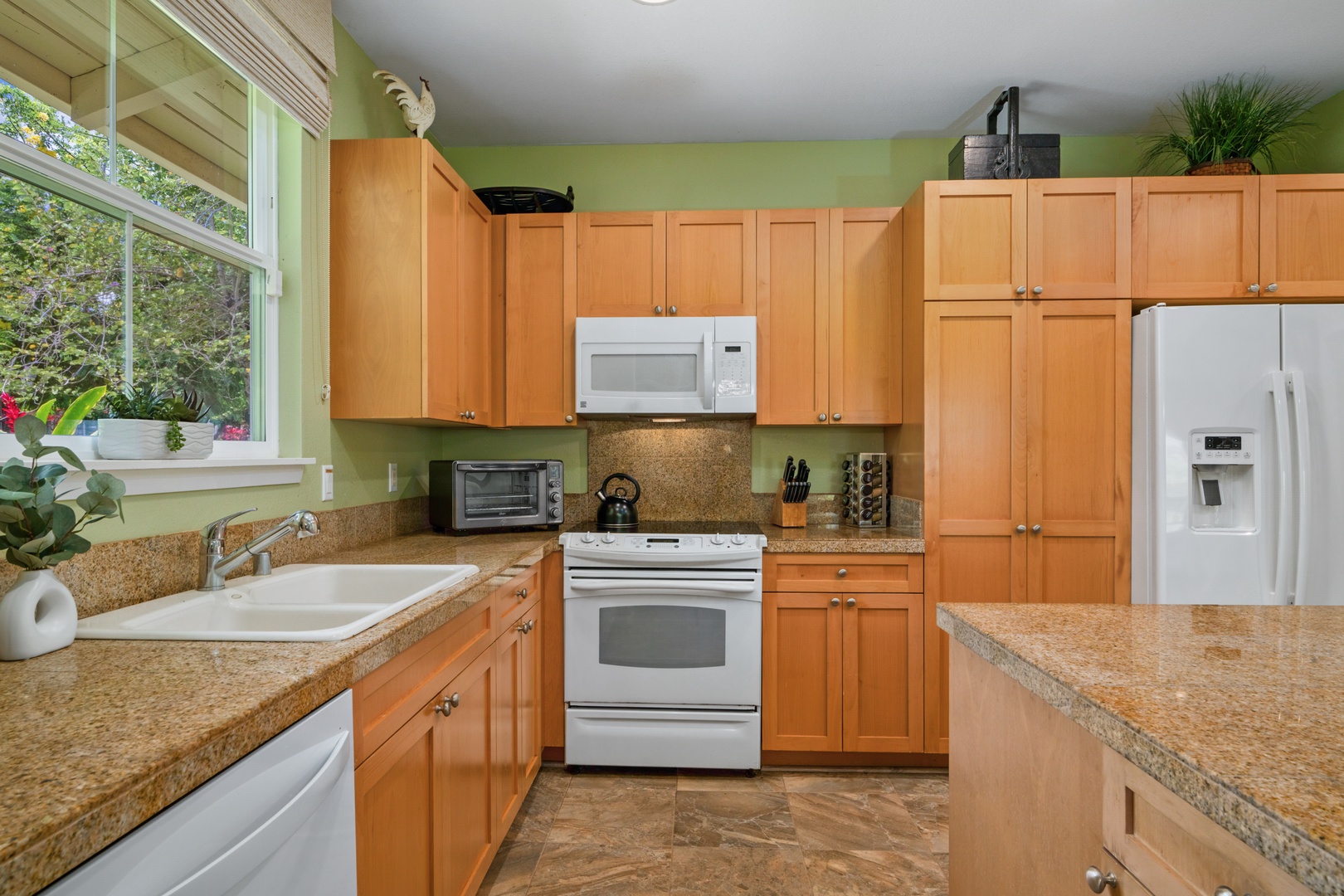 Princeville Vacation Rentals, Kaimana Villa - Cook your favorite meals in this fully equipped kitchen with granite countertops, warm wood cabinets, and modern appliances.