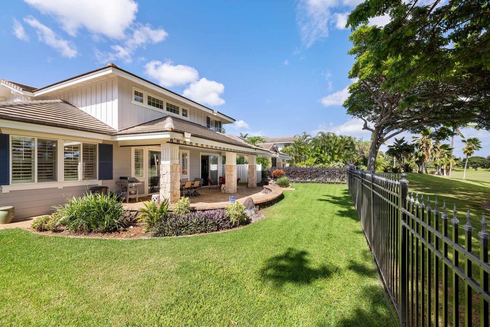 Modern property with manicured grounds overlooking golf course fairways, featuring covered lanai and tropical landscaping.