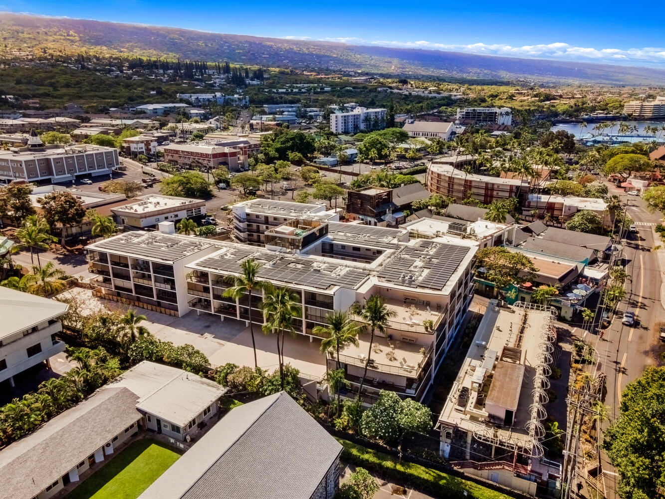 Kailua Kona Vacation Rentals, Kona Plaza 201 - Aerial view of the property nestled in a vibrant Hawaiian community with mountains stretching to the horizon.
