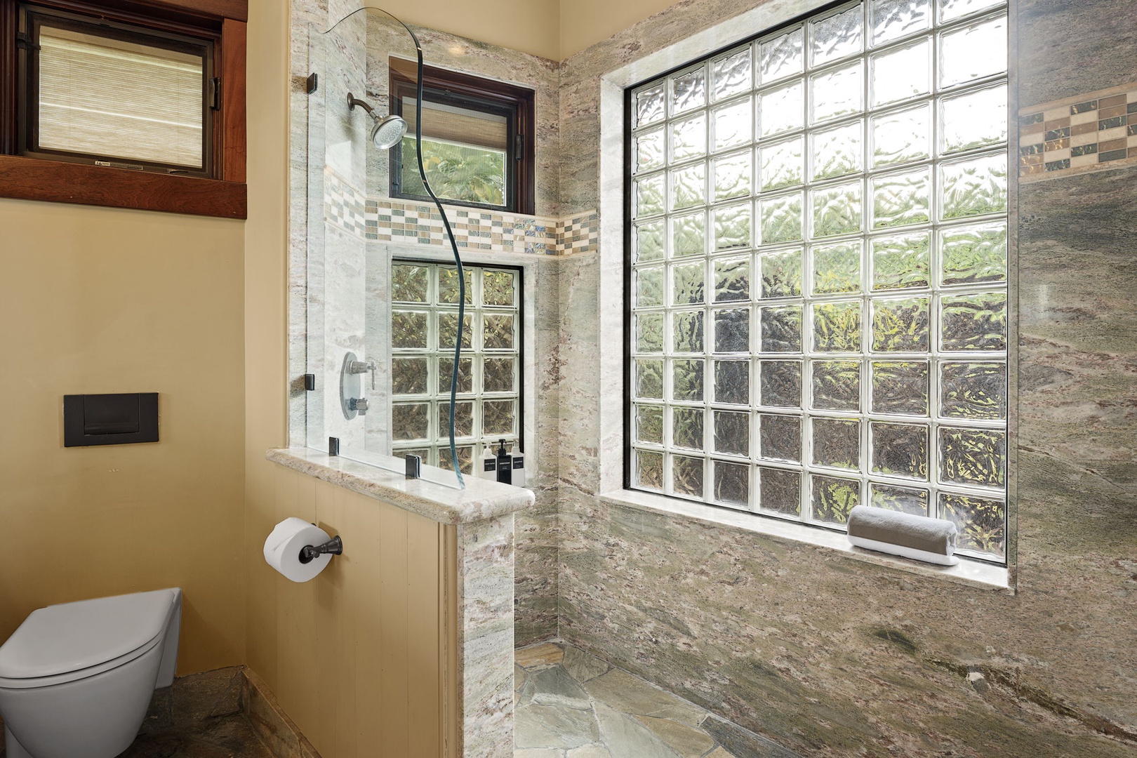 Kamuela Vacation Rentals, Hale Konane - Luxurious walk-in shower with floor-to-ceiling stone finishes and abundant natural light.