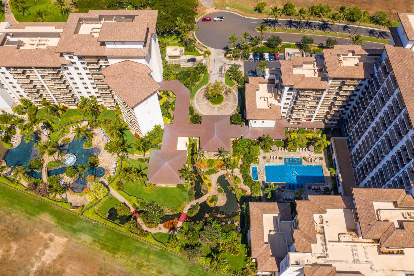 Kapolei Vacation Rentals, Ko Olina Beach Villas B604 - Aerial view of a tropical resort complex featuring multiple swimming pools, lush gardens, and modern accommodations surrounded by palm trees.