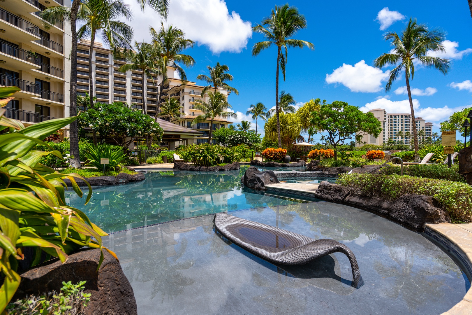 Another pool with a lounger set in the shallows, rock and palms around it.