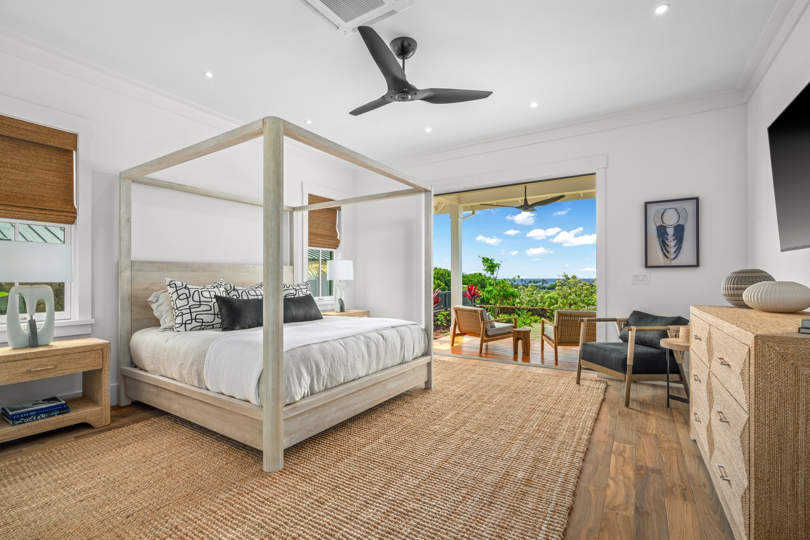 Koloa Vacation Rentals, Makani Kai - The primary suite frames its four-poster bed and walk out lanai against the open green outside.