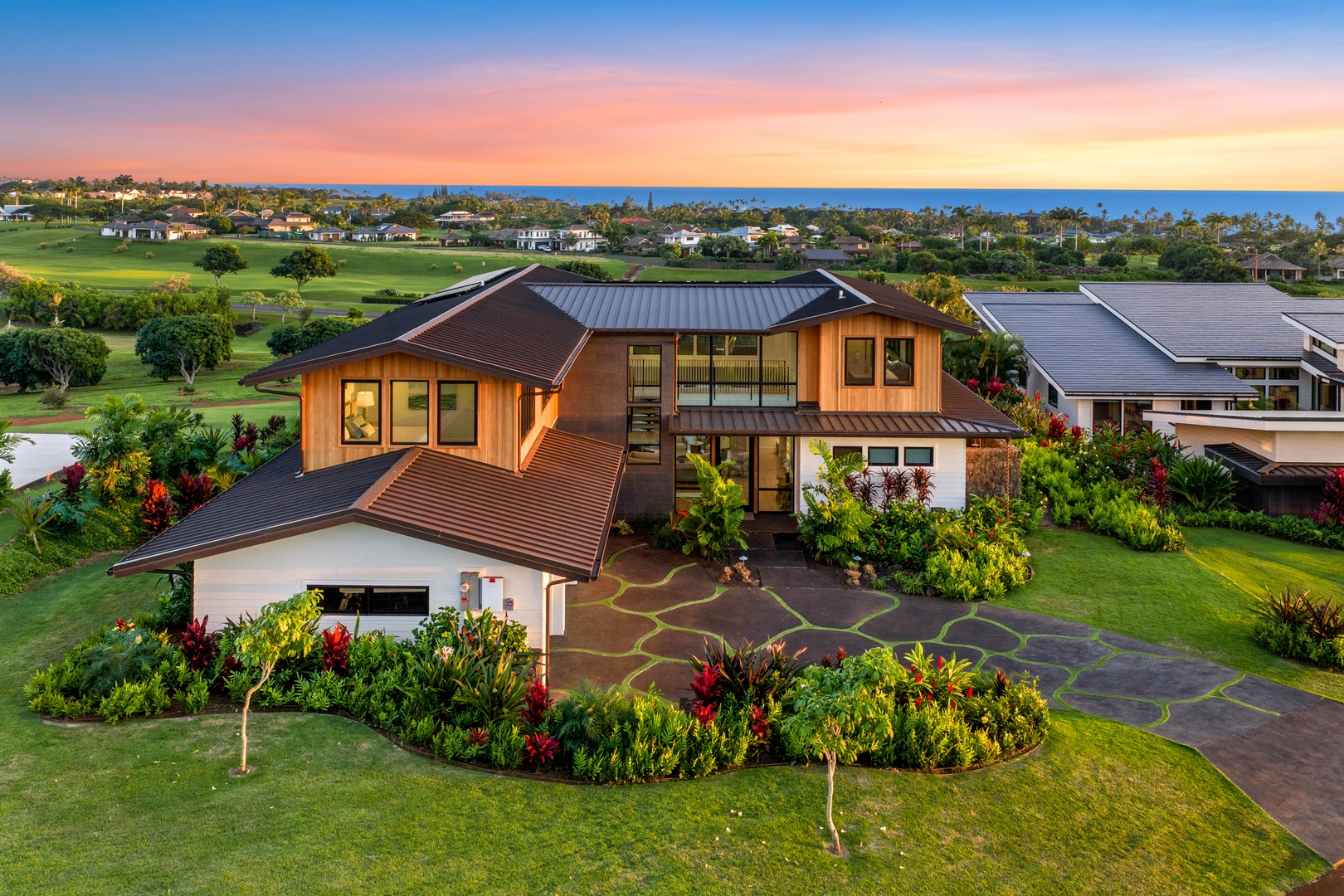 Koloa Vacation Rentals, Hale Laule'a at Kukui'ula - Your luxury home situated on pristine golf course with ocean views and tropical landscaping during golden hour.