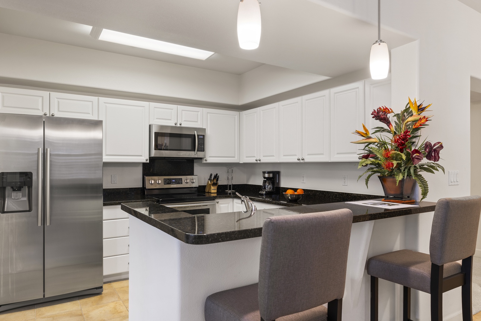 The well-equipped kitchen features granite countertops, stainless steel appliances, and bar seating for casual dining.