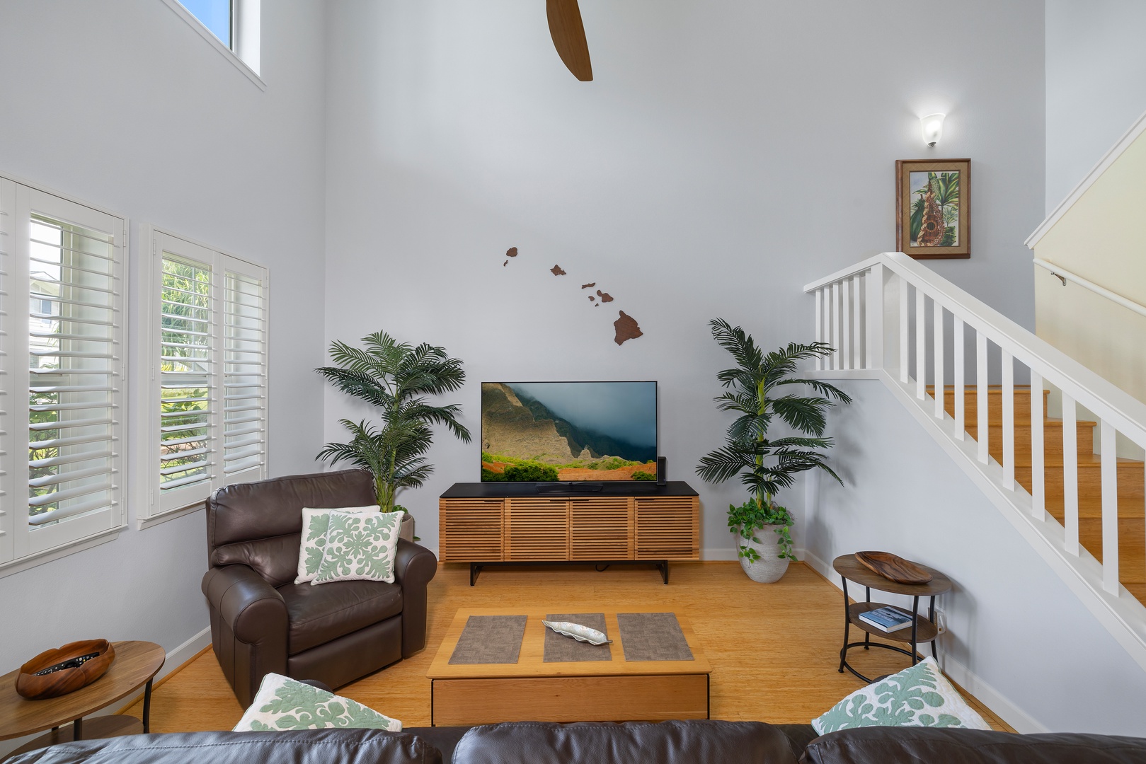 Relax in your bright living room featuring soaring ceilings, warm wood floors, and tropical touches that create the perfect Hawaiian atmosphere.