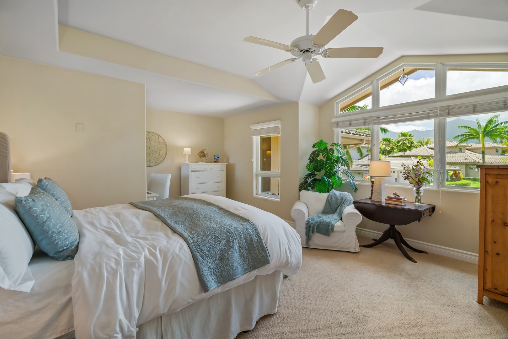 Princeville Vacation Rentals, Noelani Kai - Plush  primary bed with a reading nook, immersed in warm lights as the sun shines through the large window pane.